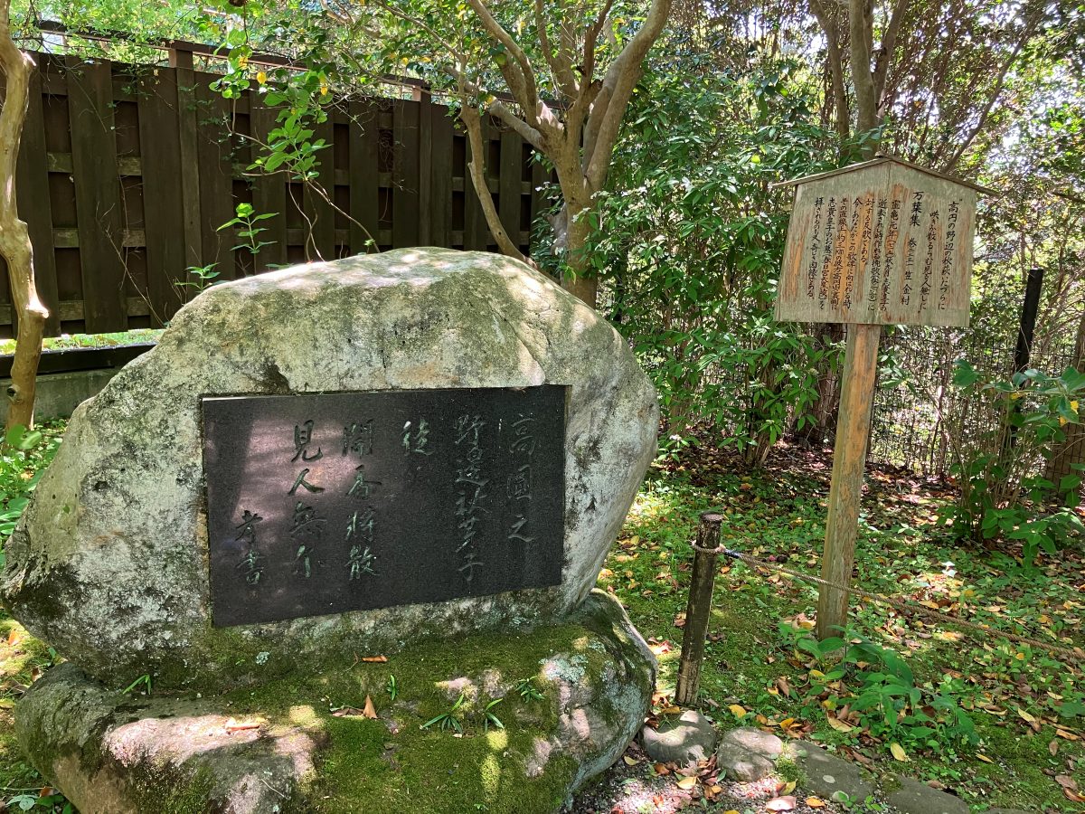 Byakugoji's Man'yoshu poem stone — a large natural boulder engraved with the poem, with a wooden signboard to the right
