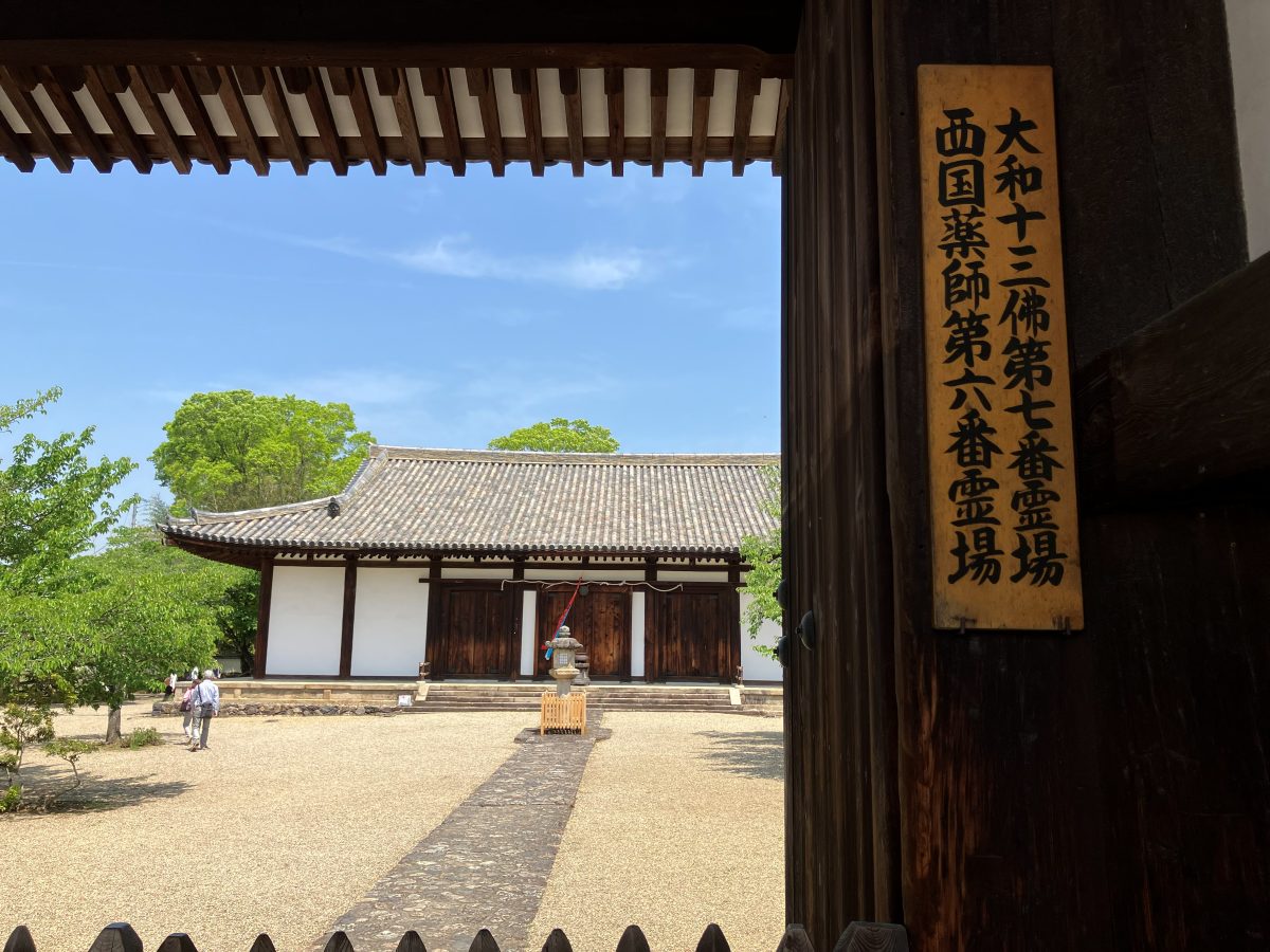 The main hall of Shin-Yakushiji seen through the South Gate, with pilgrimage plaques on the gate pillar