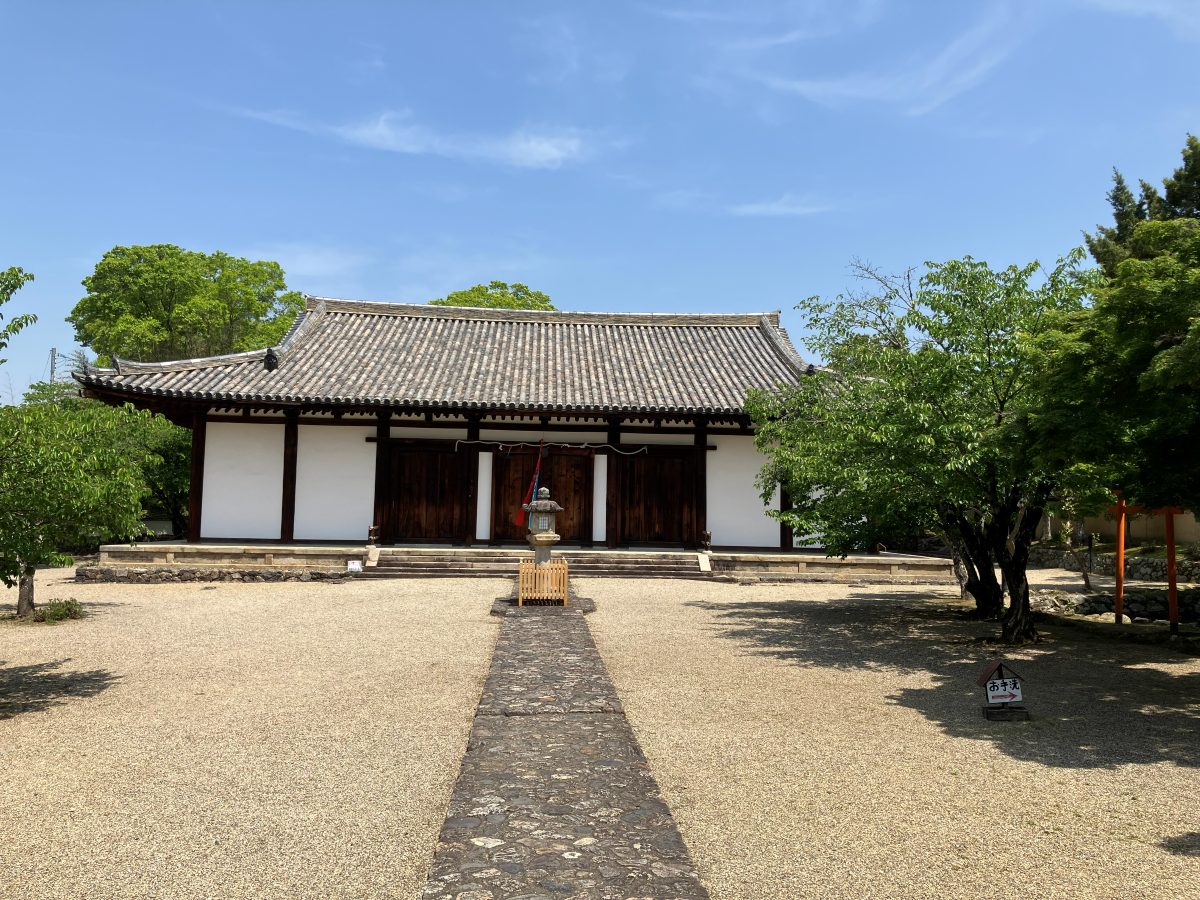 The main hall of Shin-Yakushiji — a Nara-period building with white walls and a broad tiled roof, with a stone path leading to it