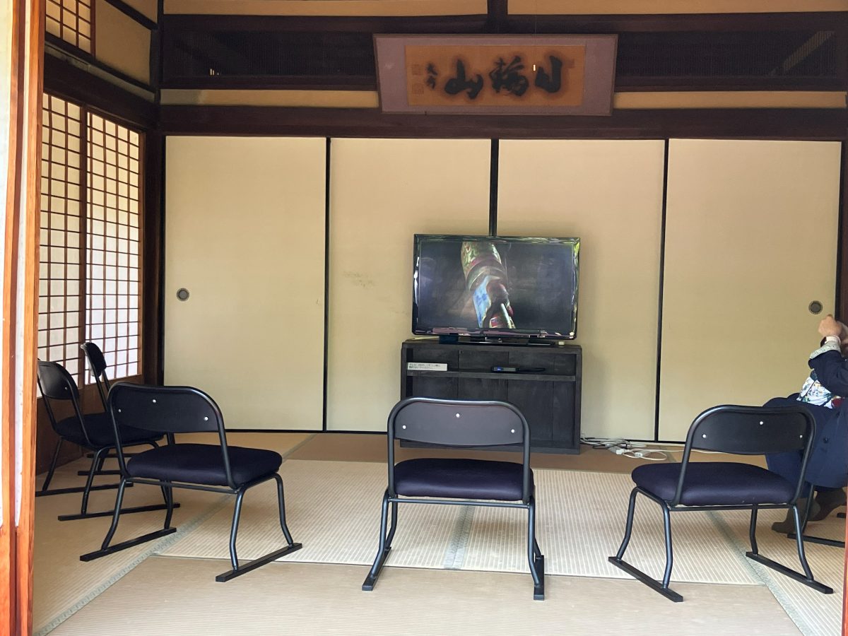 The video room at Shin-Yakushiji — chairs on tatami mats beneath a framed plaque reading Nichirin-zan