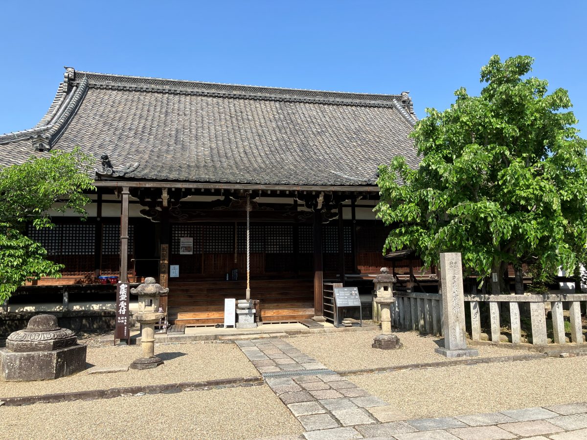 Aizen-do Hall at Saidaiji — a hall at the end of a stone path lined with lanterns and a stone pillar